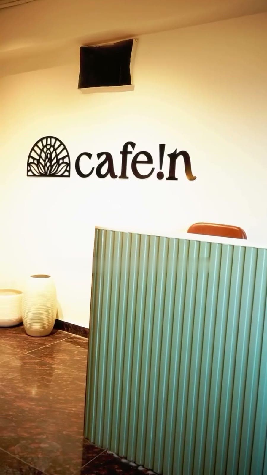 The cafe!n logo on a warm white wall beside the fluted counter