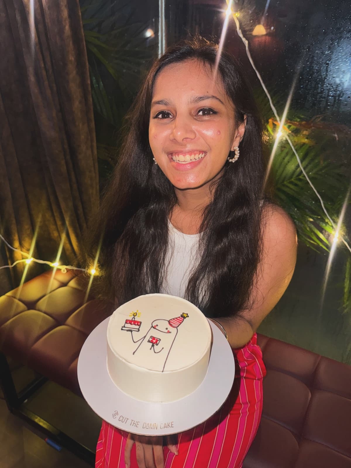 A guest smiling with her birthday cake under sparkling lights