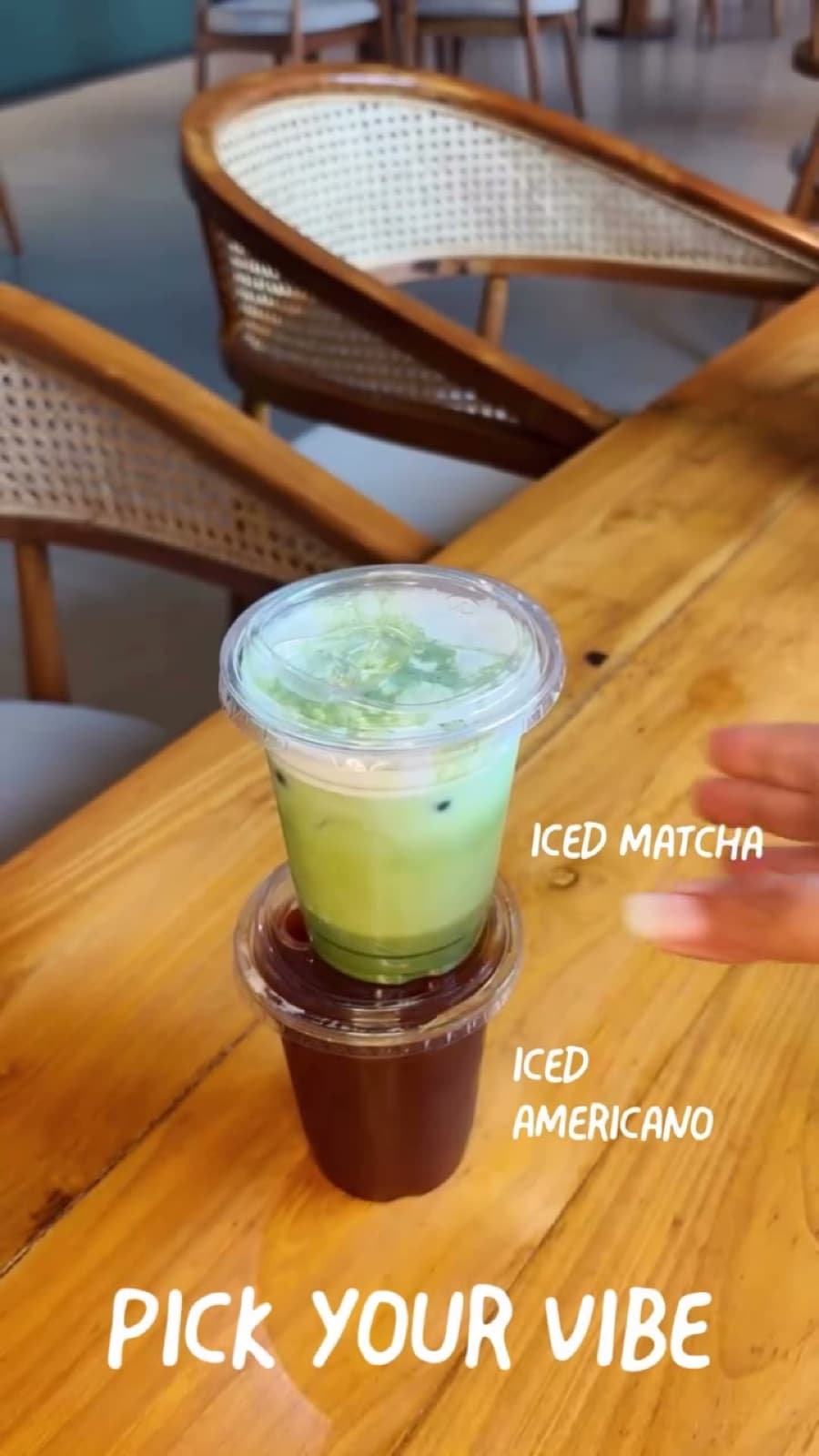 An iced matcha stacked on an iced Americano beside rattan chairs